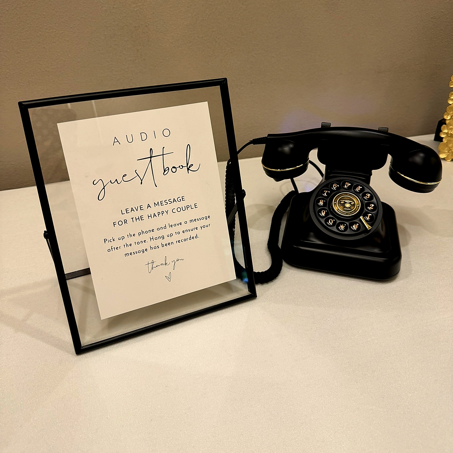 Black vintage rotary phone audio guestbook with framed instruction sign at a wedding reception