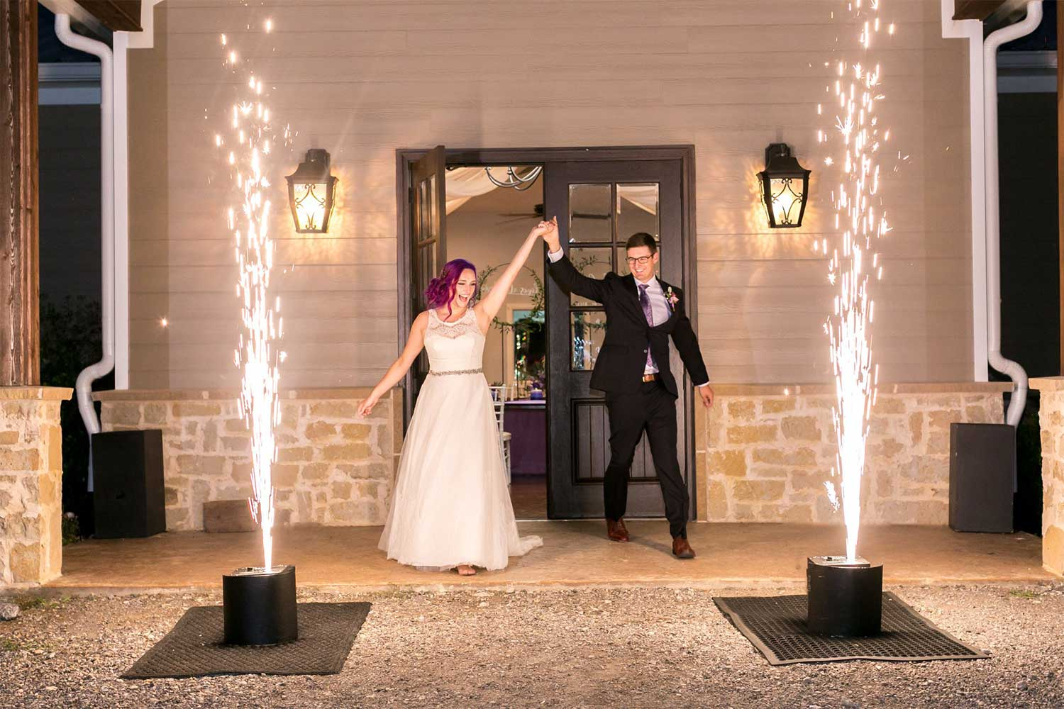 Newlyweds making a grand entrance flanked by twin cold-spark fountains